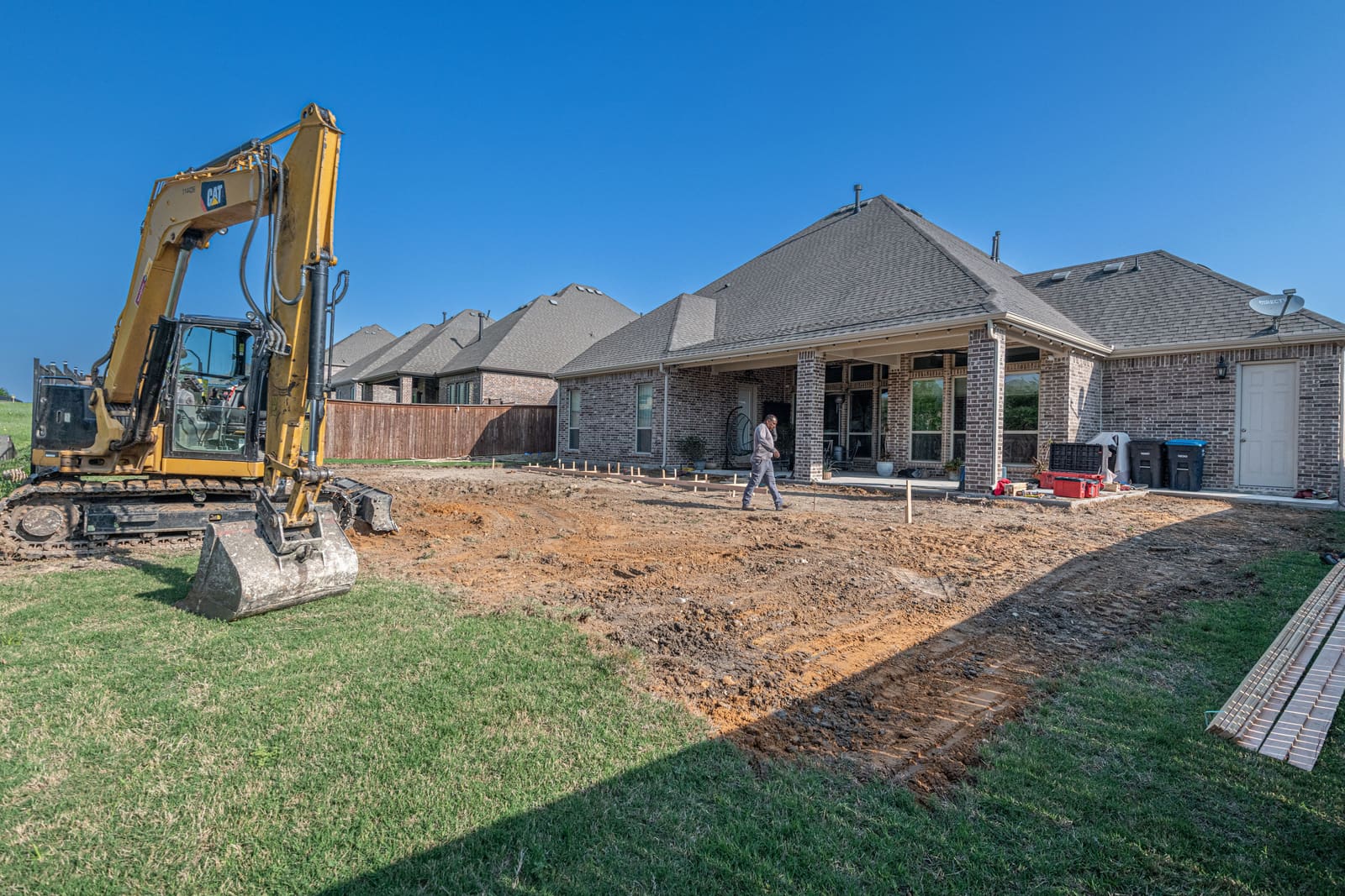 Excavator working in a suburban backyard during a pool removal job